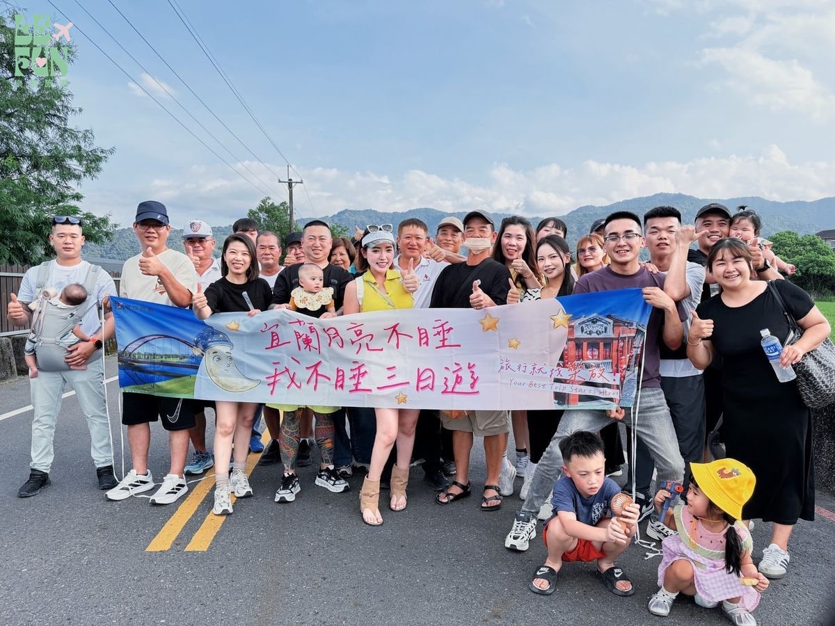 團體旅客與孩童在戶外舉布條合照
