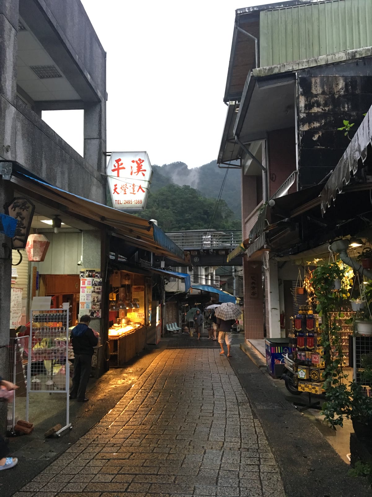 新北平溪老街雨後巷道、店家燈光與山城鐵道橋